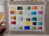 Das Bild zeigt eine Pappe mit aufgeklebtem Papier, das Proben der genutzten Farben enthält.