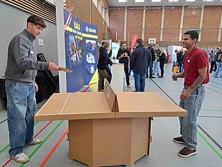 Messebild am Stand von Kollmer Bau, wo eine Tischtennisplatte steht, an der zwei Personen Spielen.