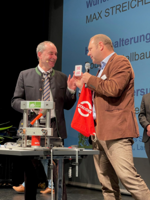 Stefan Weinberger von der Firma MAX STREICHER übergibt eine Erinnerung an Staatsminister Hubert Aiwanger
