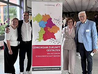 Gruppenbild vor einem SCHULEWIRTSCHAFT Bayern Plakat