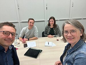 Selfie von vier Personen, die an einem Tisch sitzen