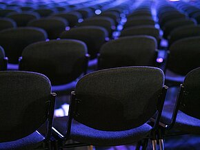 Bild von aneinandergereihten Stühlen in blau und schwarz